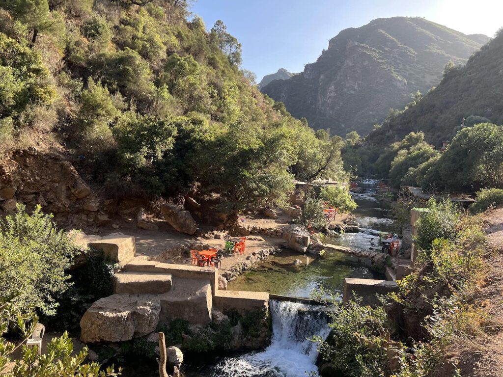 waterfall with chairs in the pool and mountains behind in arkchour morocco